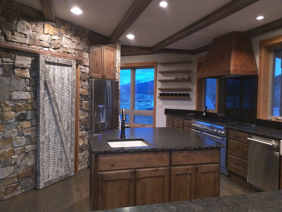 Design ideas for a mid-sized country l-shaped separate kitchen in Denver with an undermount sink, flat-panel cabinets, distressed cabinets, granite benchtops, black splashback, stainless steel appliances, dark hardwood floors, with island and beige floor.