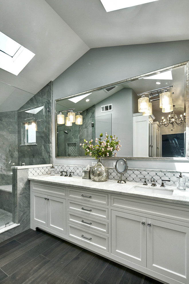 This is an example of a large transitional master bathroom in San Francisco with beaded inset cabinets, white cabinets, a freestanding tub, an alcove shower, a two-piece toilet, gray tile, porcelain tile, grey walls, porcelain floors, an undermount sink, marble benchtops, grey floor, a hinged shower door and white benchtops.