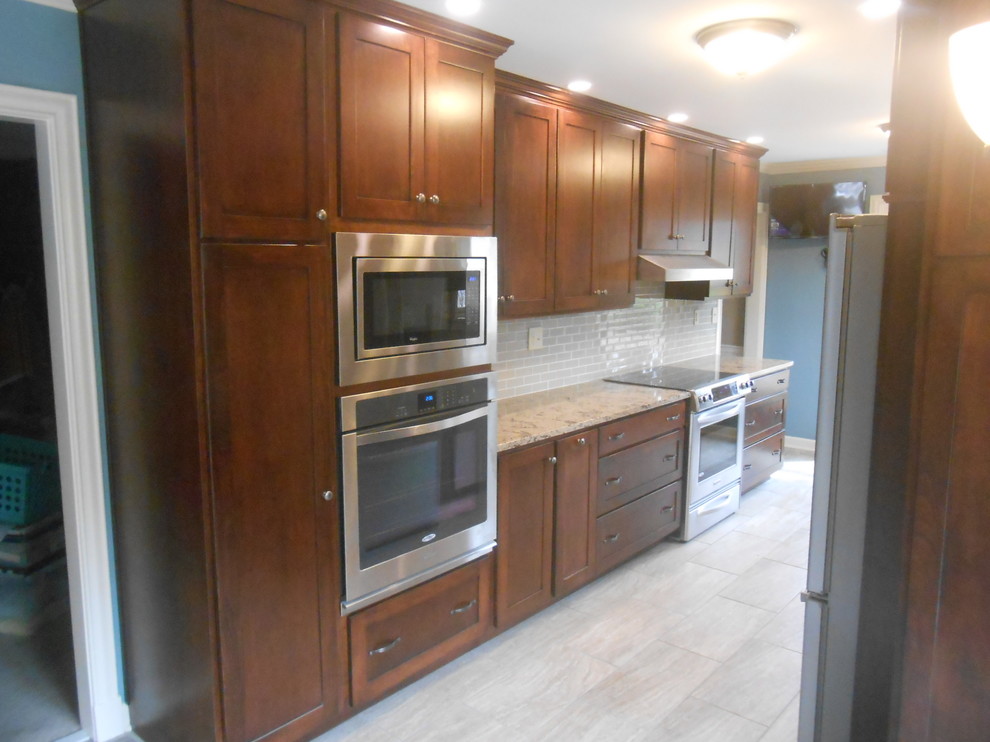 Example of a mid-sized transitional galley porcelain tile eat-in kitchen design with an undermount sink, shaker cabinets, dark wood cabinets, quartz countertops, beige backsplash, glass sheet backsplash, stainless steel appliances, blue walls and no island