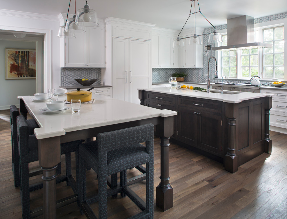 Eat-in kitchen - large transitional l-shaped medium tone wood floor and brown floor eat-in kitchen idea in Chicago with a double-bowl sink, recessed-panel cabinets, solid surface countertops, gray backsplash, glass tile backsplash, stainless steel appliances, two islands and white countertops