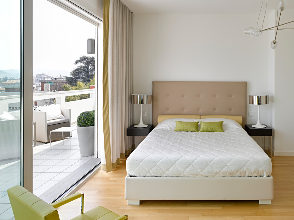 This is an example of a mid-sized contemporary master bedroom in Milan with white walls and light hardwood floors.
