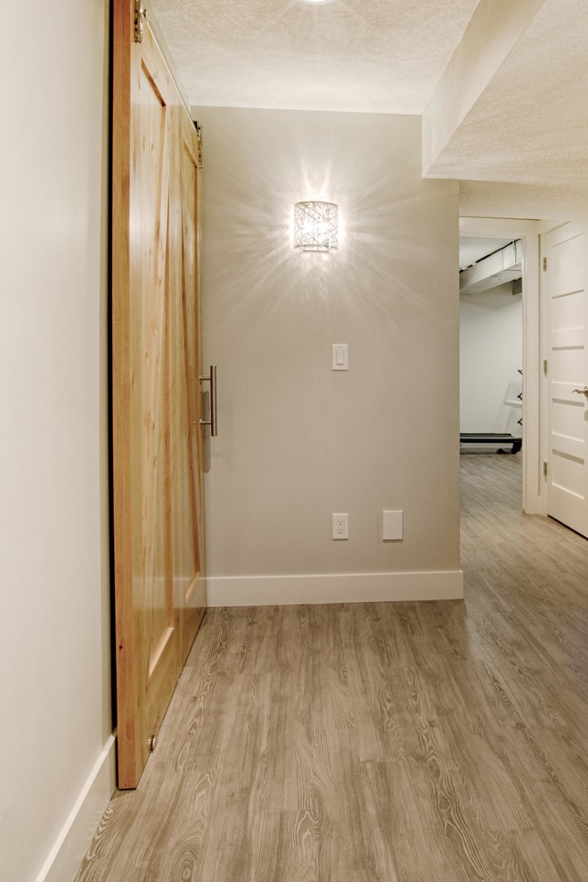 Inspiration for a large rustic look-out light wood floor basement remodel in Calgary with white walls, a standard fireplace and a brick fireplace