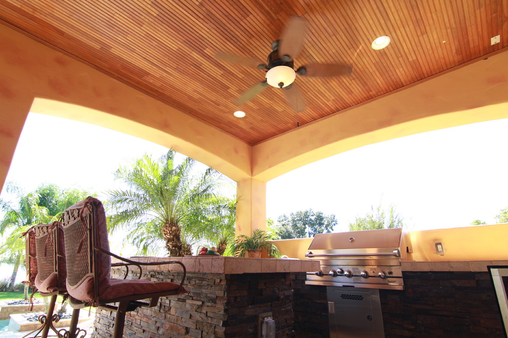 Mediterranean patio in Tampa with natural stone pavers and an outdoor kitchen.