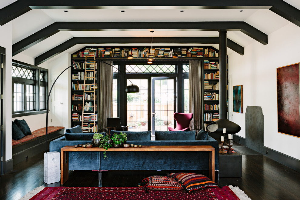 This is an example of an arts and crafts living room in Portland with a library, a hanging fireplace, no tv, white walls, dark hardwood floors and black floor.