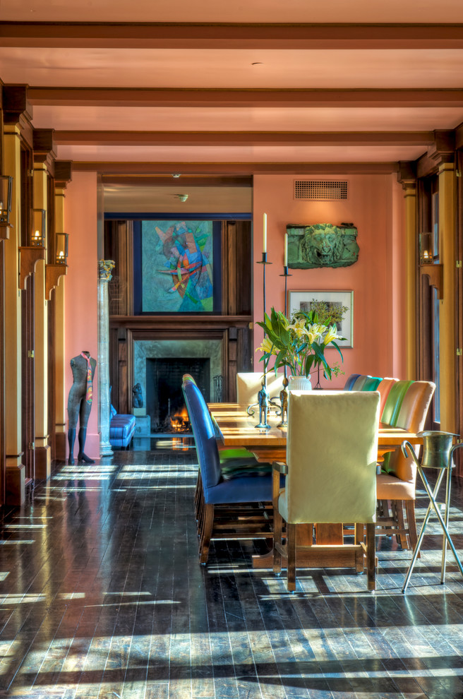 Photo of a traditional separate dining room in New York with dark hardwood floors, a standard fireplace and orange walls.