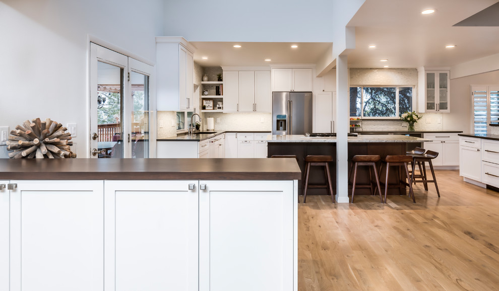 Example of a large transitional light wood floor eat-in kitchen design in Denver with a single-bowl sink, shaker cabinets, white cabinets, quartz countertops, white backsplash, marble backsplash, stainless steel appliances, two islands and gray countertops