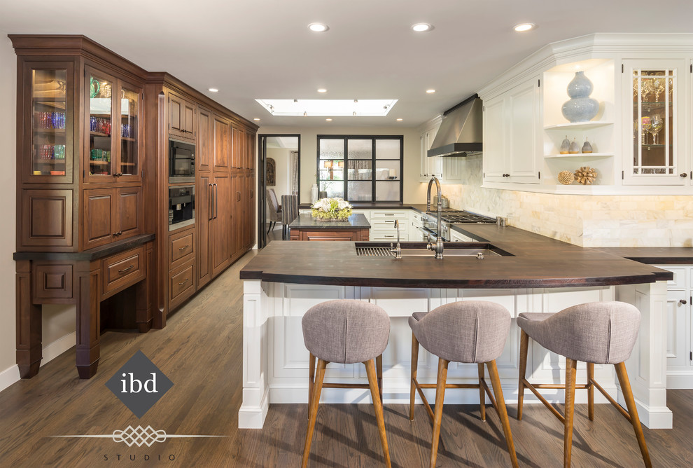 Enclosed kitchen - mid-sized transitional u-shaped enclosed kitchen idea in Phoenix with an undermount sink, beaded inset cabinets, white cabinets, wood countertops, white backsplash, stone tile backsplash, stainless steel appliances and an island