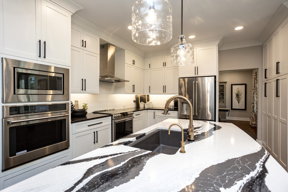 This is an example of a large transitional u-shaped open plan kitchen in Other with a single-bowl sink, recessed-panel cabinets, white cabinets, quartz benchtops, white splashback, granite splashback, stainless steel appliances, dark hardwood floors, with island, brown floor and grey benchtop.