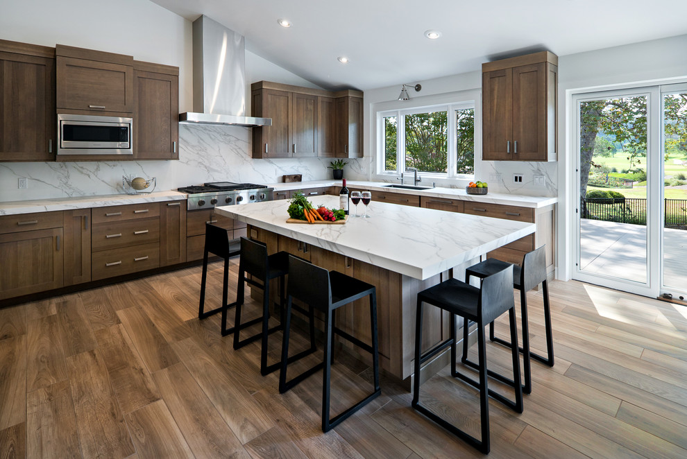 Contemporary l-shaped kitchen in Orange County with shaker cabinets, dark wood cabinets, white splashback, stainless steel appliances, dark hardwood floors and with island.