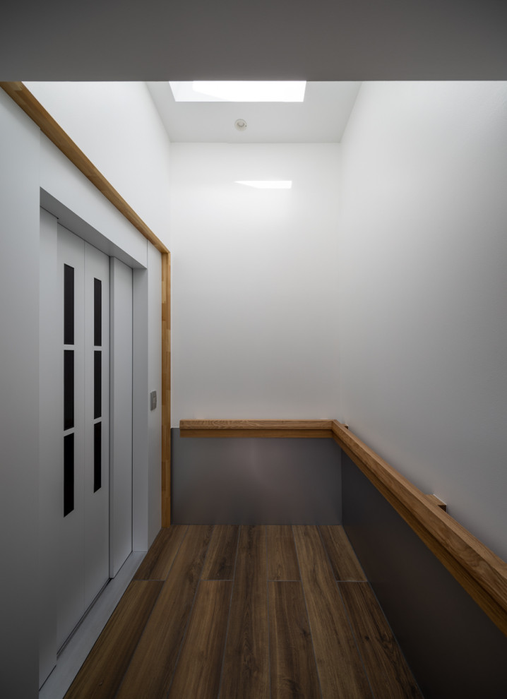 Ispirazione per un piccolo ingresso o corridoio design con pareti bianche, pavimento in gres porcellanato, una porta scorrevole, una porta grigia, pavimento marrone, soffitto in perlinato e pareti in perlinato