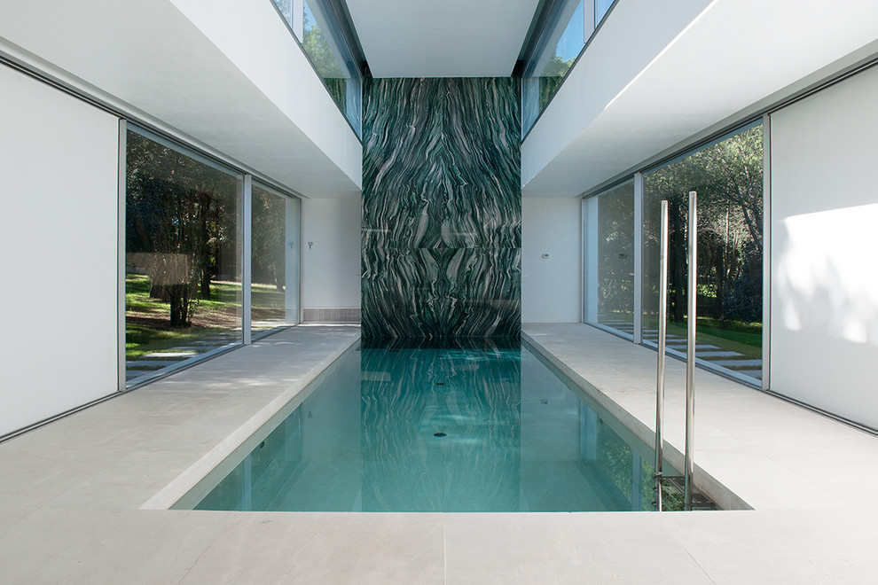Photo of a large contemporary indoor rectangular pool in Madrid with a pool house and concrete slab.