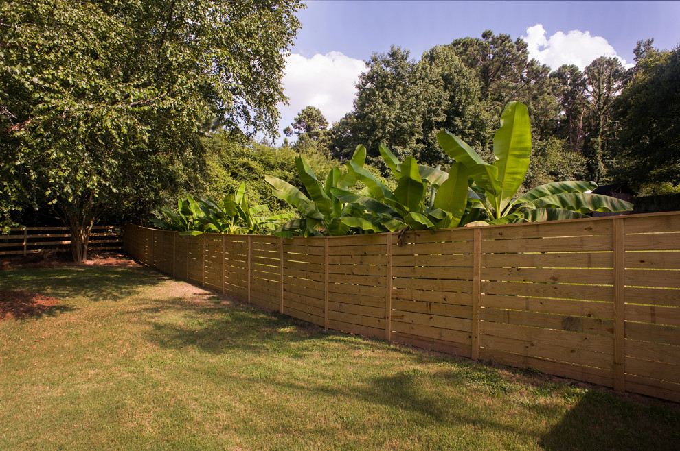 На фото: участок и сад на заднем дворе с с деревянным забором