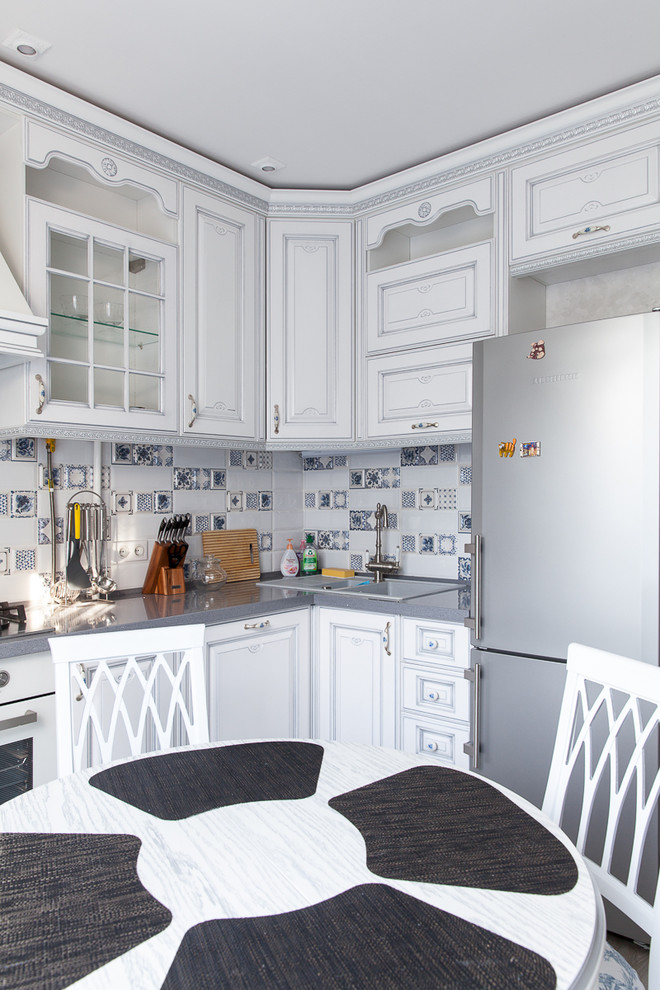 This is an example of a traditional separate kitchen in Moscow with a double-bowl sink, raised-panel cabinets, white cabinets, multi-coloured splashback, white appliances and no island.