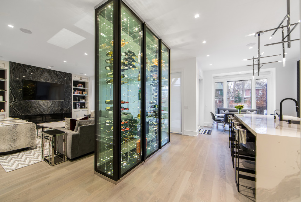 Photo of a mid-sized contemporary wine cellar in Toronto with light hardwood floors, display racks and beige floor.