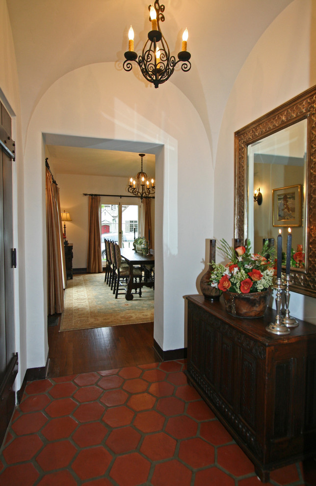 This is an example of a mediterranean foyer in San Diego with white walls, terra-cotta floors and a single front door.