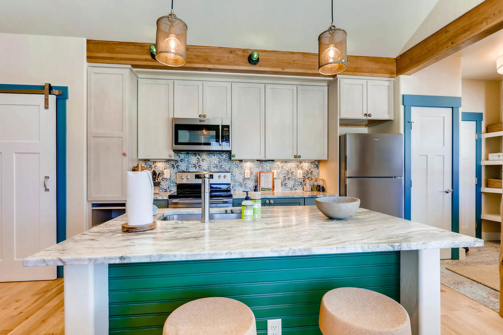 Small transitional single-wall light wood floor and brown floor open concept kitchen photo in Denver with an undermount sink, shaker cabinets, gray cabinets, quartz countertops, blue backsplash, mosaic tile backsplash, stainless steel appliances, an island and gray countertops