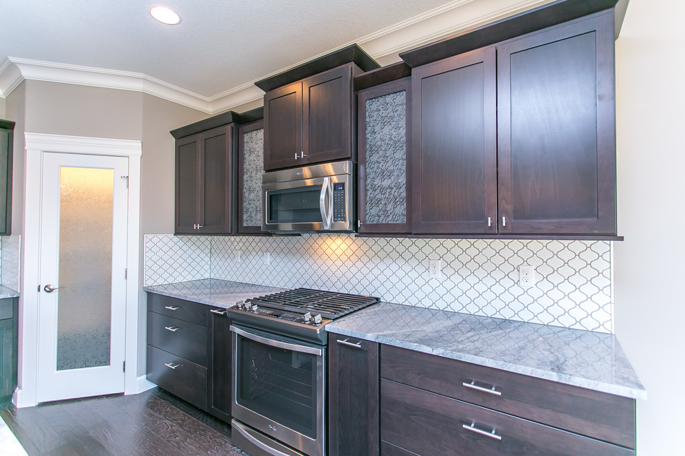 Open concept kitchen - mid-sized transitional l-shaped dark wood floor open concept kitchen idea in Seattle with an undermount sink, shaker cabinets, dark wood cabinets, granite countertops, white backsplash, porcelain backsplash, stainless steel appliances and an island