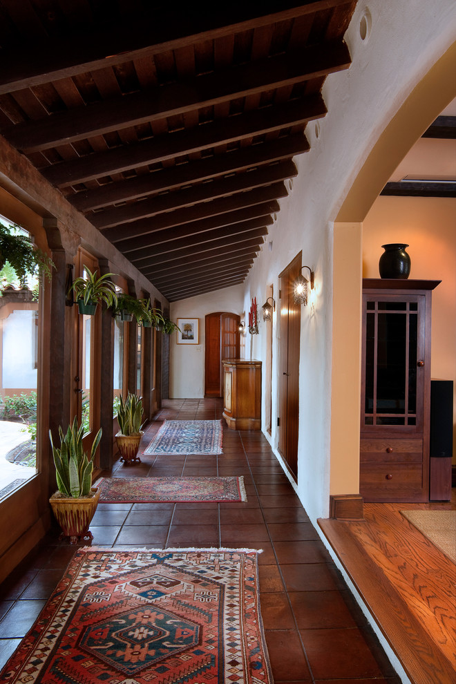 Design ideas for a mediterranean hallway in San Diego with white walls and terra-cotta floors.