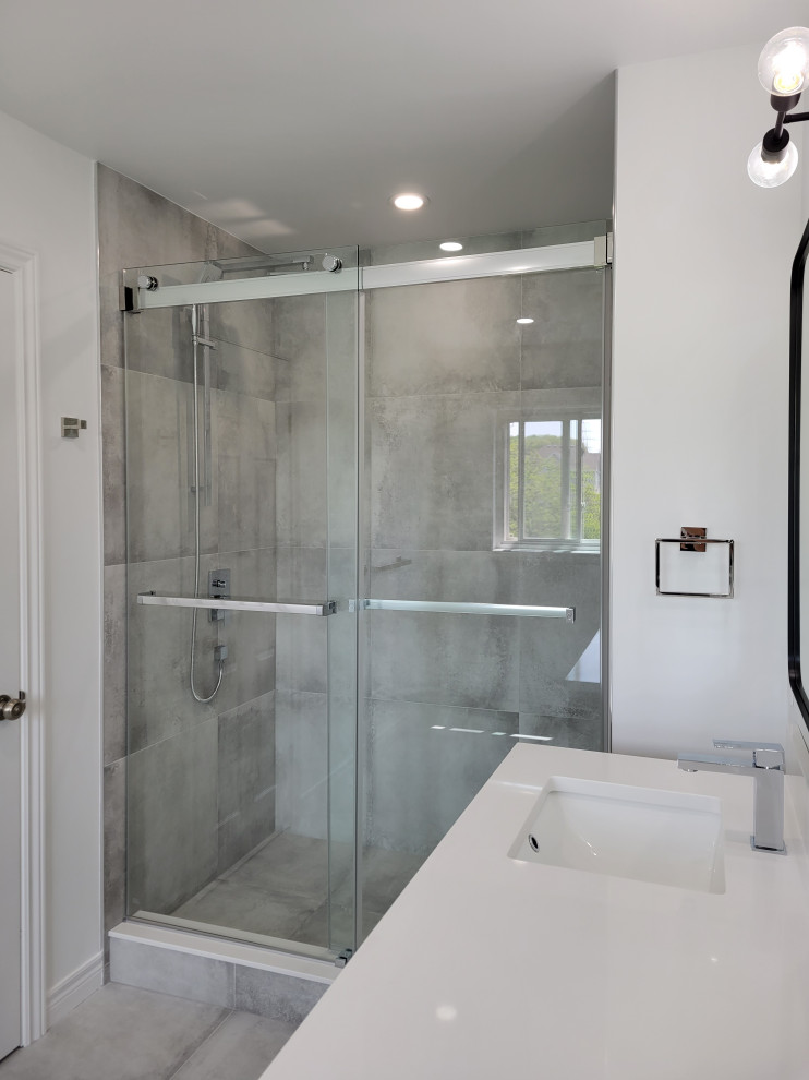 Источник вдохновения для домашнего уюта: главная ванная комната в стиле модернизм с душем в нише, серой плиткой, керамогранитной плиткой, серыми стенами, полом из керамогранита, серым полом и душем с раздвижными дверями