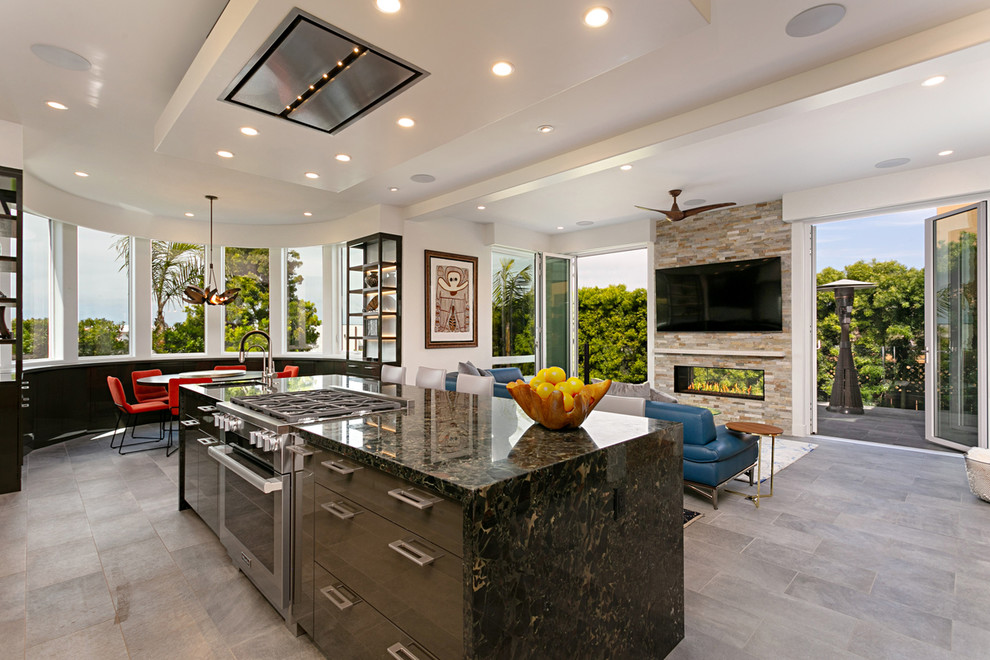 This is an example of a large contemporary l-shaped open plan kitchen in San Diego with an undermount sink, flat-panel cabinets, black cabinets, granite benchtops, white splashback, glass sheet splashback, panelled appliances, porcelain floors, with island, beige floor and black benchtop.