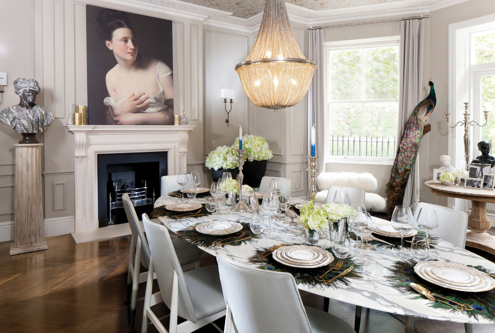 Photo of an expansive eclectic separate dining room in London with grey walls, medium hardwood floors, a standard fireplace, a stone fireplace surround and brown floor.