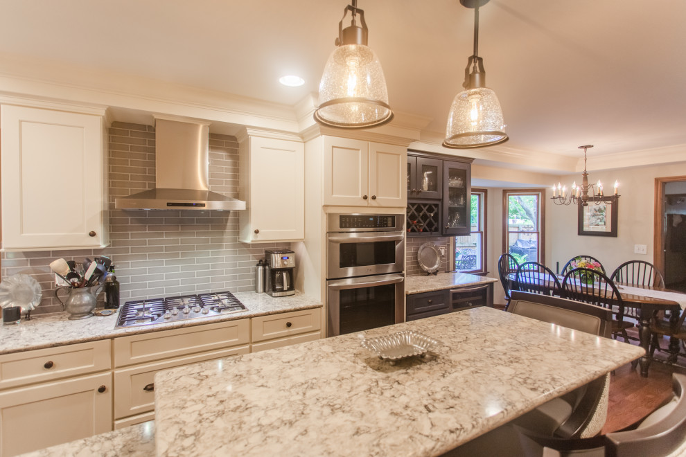 Eat-in kitchen - large transitional single-wall dark wood floor, brown floor and coffered ceiling eat-in kitchen idea in Cincinnati with a double-bowl sink, shaker cabinets, white cabinets, granite countertops, gray backsplash, subway tile backsplash, stainless steel appliances, an island and multicolored countertops