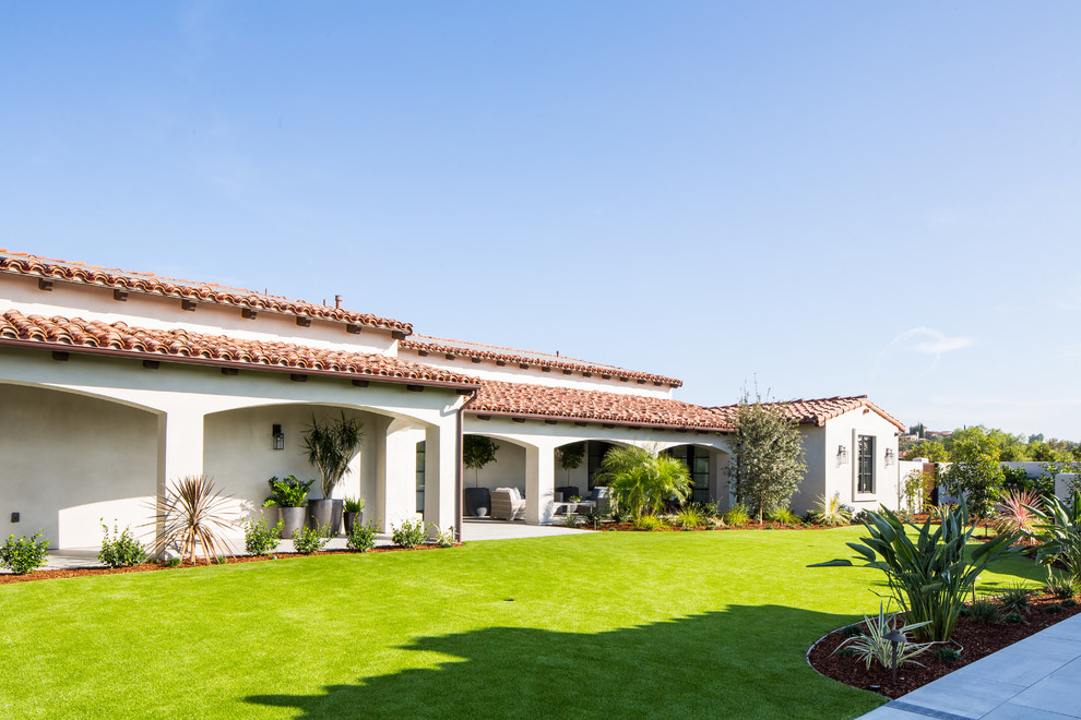 This is an example of an expansive mediterranean one-storey stucco white house exterior in San Diego with a tile roof.