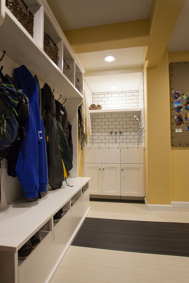 Photo of a large transitional l-shaped utility room in Seattle with an integrated sink, shaker cabinets, white cabinets, laminate benchtops, yellow walls, linoleum floors and a side-by-side washer and dryer.