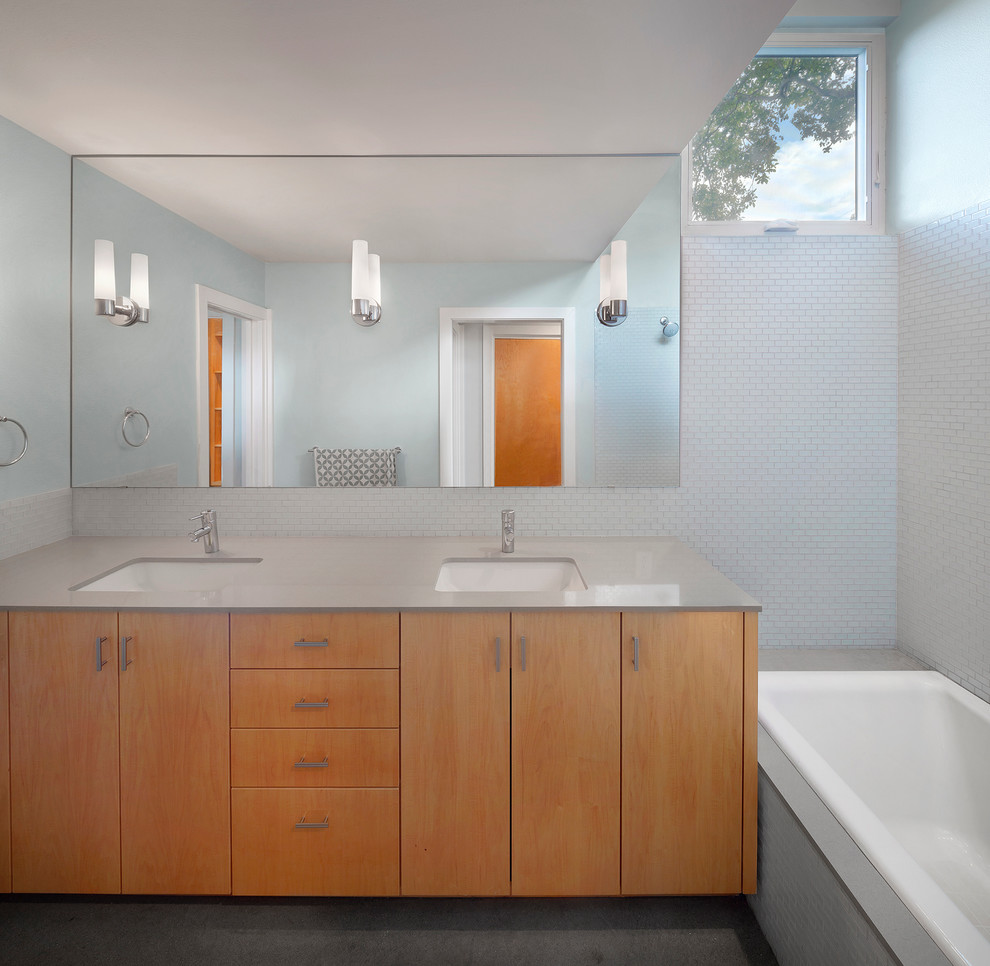 Design ideas for a mid-sized contemporary master bathroom in Austin with an undermount sink, flat-panel cabinets, light wood cabinets, engineered quartz benchtops, an alcove tub, a shower/bathtub combo, a two-piece toilet, white tile, glass tile, blue walls and concrete floors.