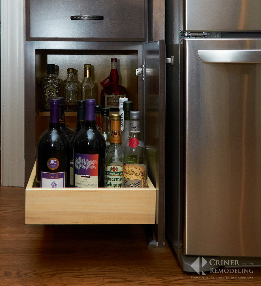 Example of a transitional light wood floor eat-in kitchen design with shaker cabinets, dark wood cabinets, granite countertops, beige backsplash, glass tile backsplash, stainless steel appliances and an island