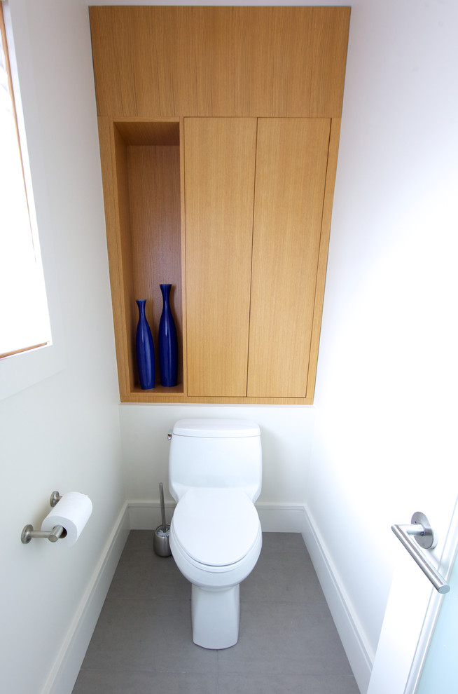 This is an example of a contemporary powder room in Vancouver with flat-panel cabinets, light wood cabinets, a two-piece toilet, gray tile, beige walls, an integrated sink and concrete benchtops.