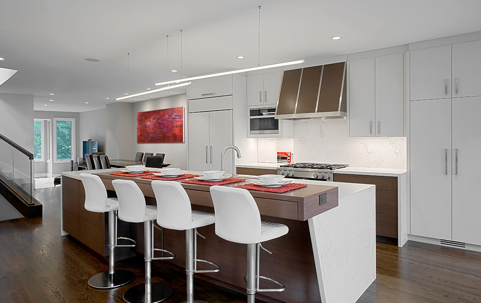 Photo of a large contemporary single-wall eat-in kitchen in Chicago with flat-panel cabinets, dark hardwood floors, with island, white cabinets, white splashback, panelled appliances, brown floor, quartz benchtops, marble splashback and white benchtop.