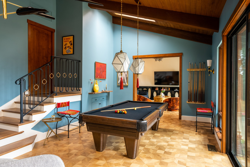 Imagen de sala de juegos en casa bohemia con paredes azules, suelo de madera en tonos medios, televisor colgado en la pared y vigas vistas