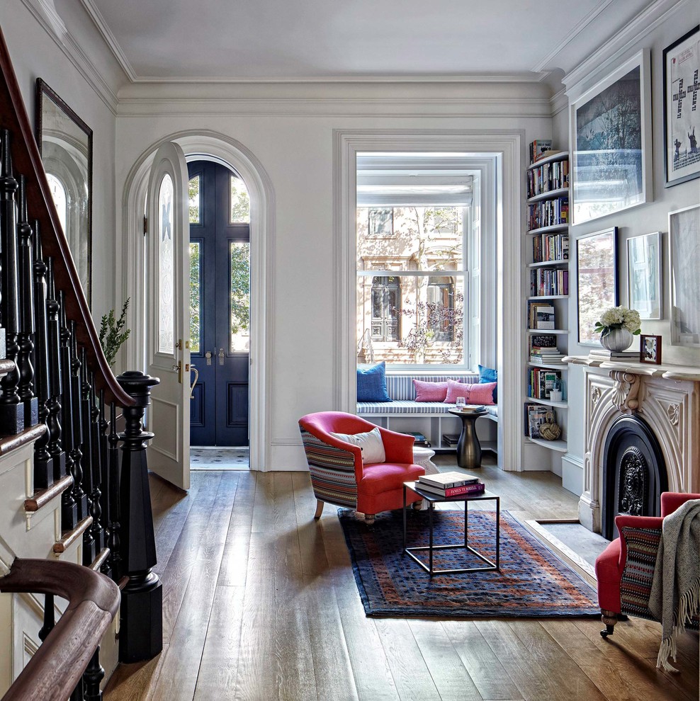 Design ideas for a transitional open concept living room in New York with a library, white walls, medium hardwood floors and a standard fireplace.