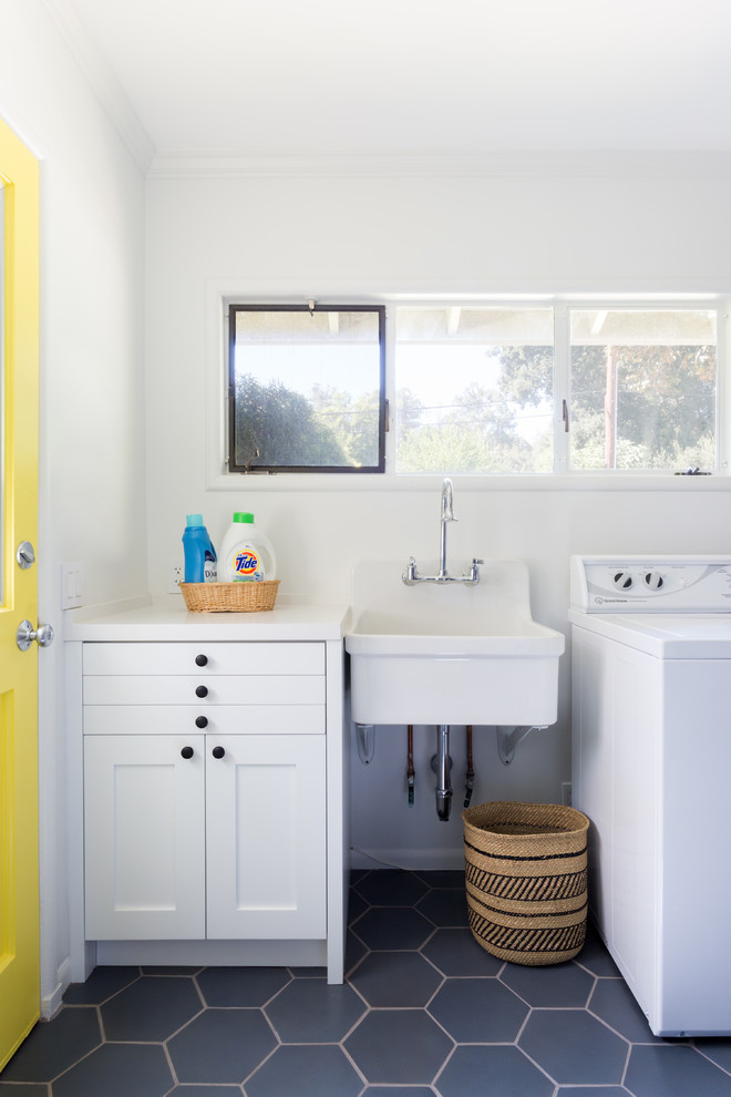 This is an example of a mid-sized traditional u-shaped utility room in Los Angeles with an utility sink, shaker cabinets, white cabinets, quartzite benchtops, white walls, ceramic floors, a side-by-side washer and dryer, black floor and white benchtop.