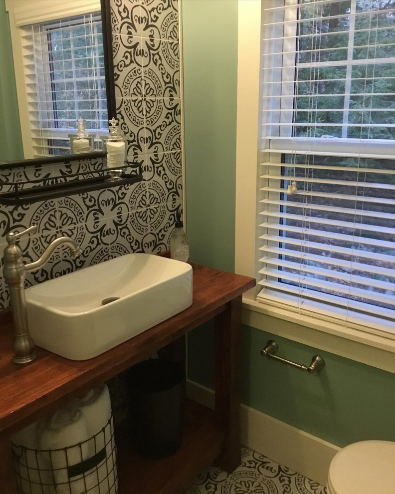 Photo of a small country bathroom in Bridgeport with open cabinets, brown cabinets, a two-piece toilet, black and white tile, porcelain tile, green walls, porcelain floors, a vessel sink, wood benchtops and brown benchtops.