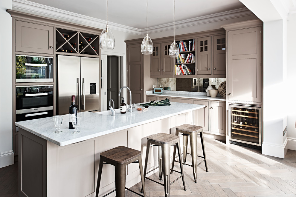 Medium sized traditional l-shaped kitchen in London with a belfast sink, beaded cabinets, brown cabinets, marble worktops, metallic splashback, mirror splashback, stainless steel appliances, dark hardwood flooring, an island and brown floors.
