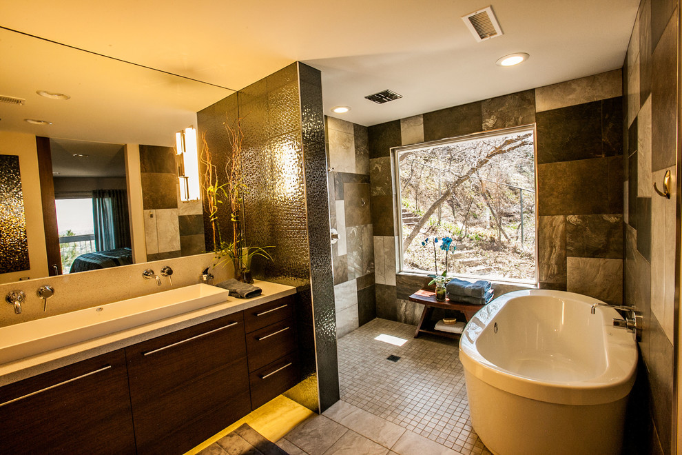 Photo of a large modern master bathroom in Salt Lake City with flat-panel cabinets, medium wood cabinets, an open shower, a bidet, gray tile, ceramic tile, beige walls, porcelain floors, a trough sink and granite benchtops.