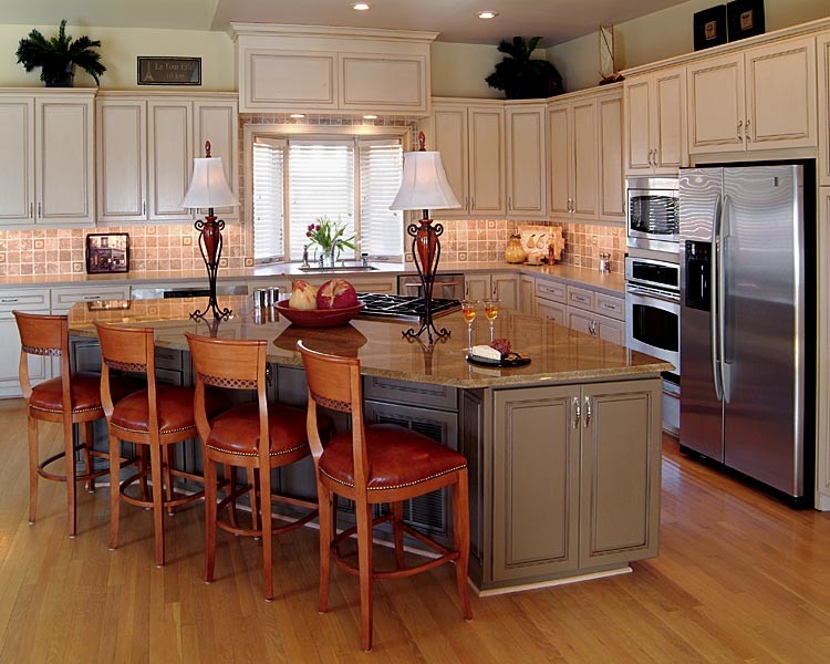Example of a mid-sized transitional u-shaped medium tone wood floor open concept kitchen design in Charlotte with an undermount sink, shaker cabinets, beige cabinets, granite countertops, beige backsplash, porcelain backsplash, stainless steel appliances and an island