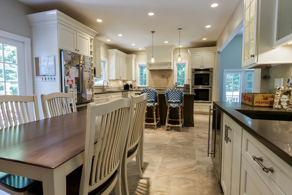 Example of a mid-sized mountain style l-shaped porcelain tile and beige floor open concept kitchen design in Bridgeport with an undermount sink, shaker cabinets, white cabinets, granite countertops, beige backsplash, porcelain backsplash, stainless steel appliances and an island