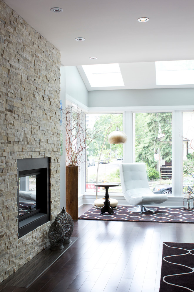 This is an example of a contemporary living room in Toronto with grey walls and a stone fireplace surround.