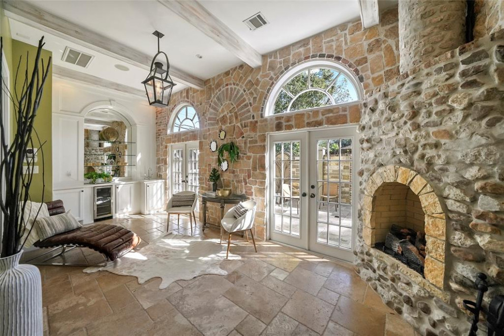 This is an example of an eclectic sunroom in Houston with a wood stove, a stone fireplace surround, beige floor and travertine floors.