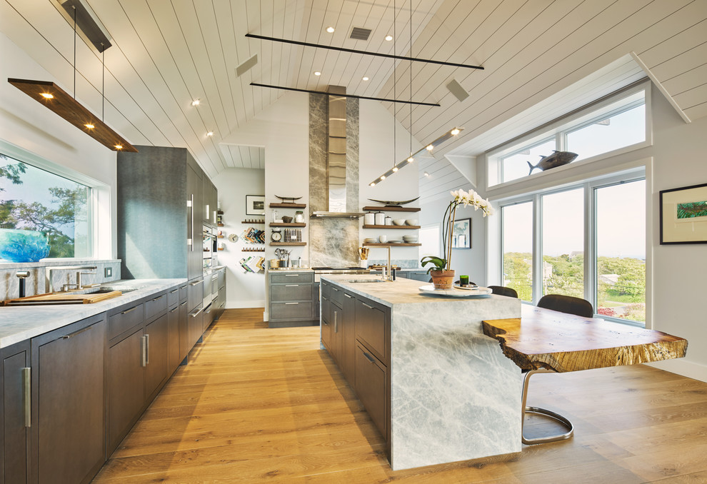 This is an example of a large midcentury l-shaped eat-in kitchen in New York with an undermount sink, flat-panel cabinets, grey cabinets, quartz benchtops, grey splashback, light hardwood floors, with island, marble splashback, stainless steel appliances and beige floor.