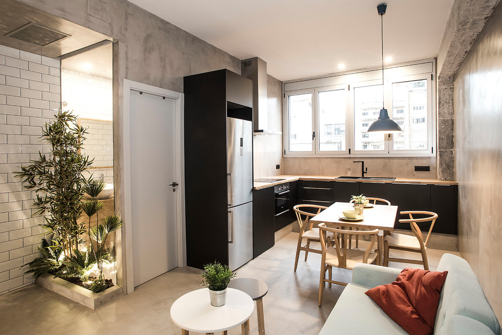 Inspiration for a mid-sized industrial l-shaped eat-in kitchen in Barcelona with black cabinets, wood benchtops, grey floor, flat-panel cabinets, grey splashback, concrete floors and no island.