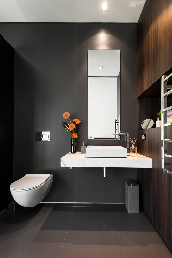 Design ideas for a mid-sized contemporary powder room in Perth with a vessel sink, dark wood cabinets, marble benchtops, a wall-mount toilet, black walls and ceramic floors.