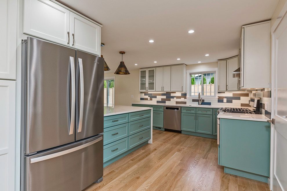 Large contemporary l-shaped eat-in kitchen in Seattle with an undermount sink, raised-panel cabinets, turquoise cabinets, quartz benchtops, multi-coloured splashback, glass tile splashback, stainless steel appliances, light hardwood floors, a peninsula and multi-coloured benchtop.