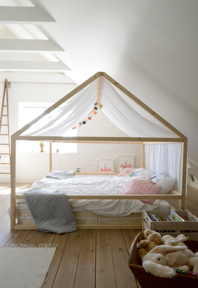 Design ideas for a large scandinavian gender-neutral kids' bedroom for kids 4-10 years old in Gothenburg with white walls and medium hardwood floors.