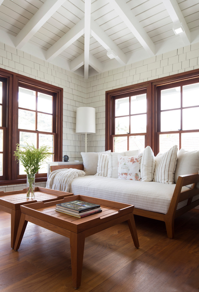 Photo of a tropical enclosed family room in Hawaii with white walls, medium hardwood floors and brown floor.
