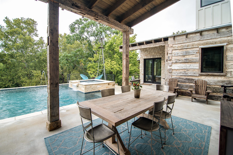 This is an example of a mid-sized country backyard patio in Austin with concrete slab and a roof extension.