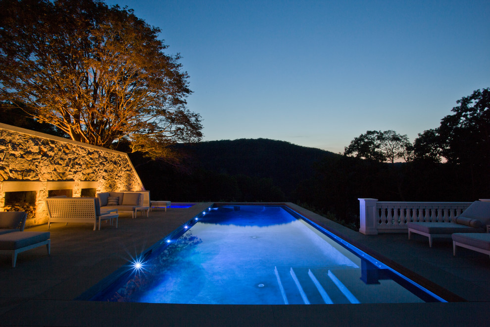 This is an example of a large arts and crafts side yard rectangular lap pool in New York with a hot tub and natural stone pavers.